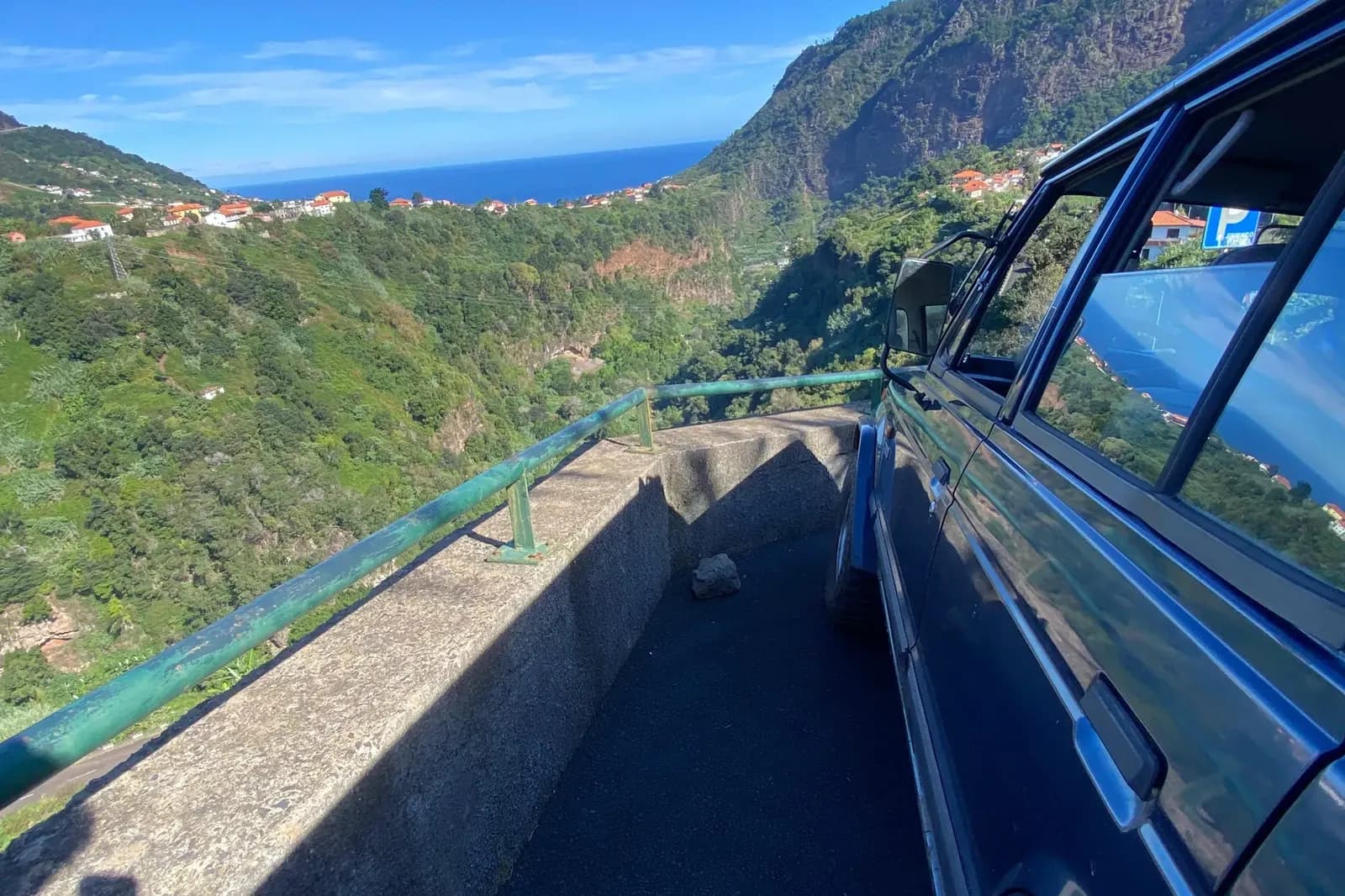 View from an open jeep towards Madeira’s green slopes, coastal homes and sea